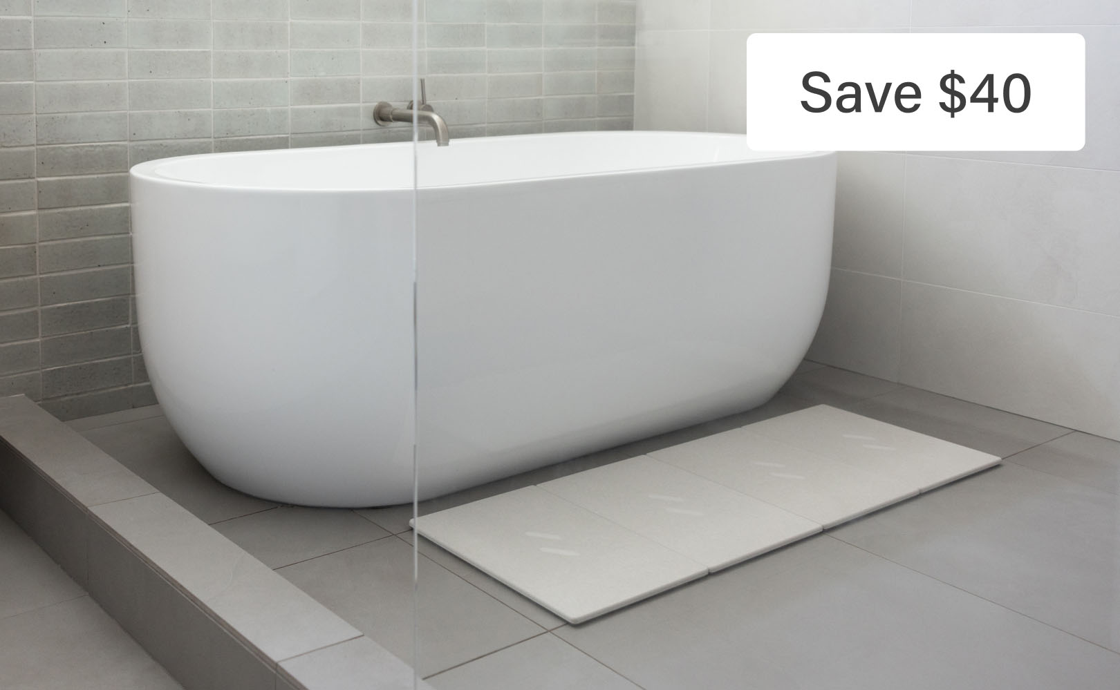 Sleek white bathtub with gray tiled wall.